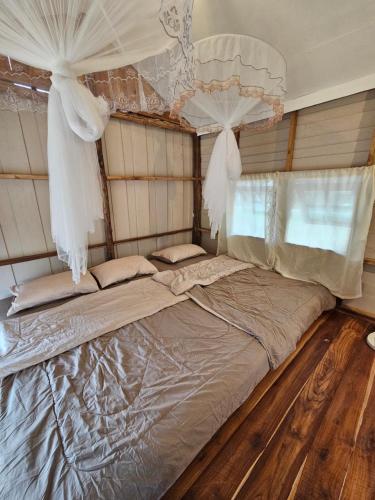 a large bed in a bedroom with curtains at PANAKLUEA Cottage & Crafts - พนาเกลือ in Ban Kham
