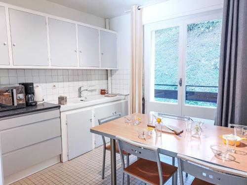 une cuisine avec des armoires blanches et une table avec des chaises dans l'établissement Apartment La côte du Parc-2 by Interhome, à Saint-Gervais-les-Bains