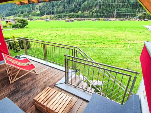 a deck with a red chair and a view of a field at Apartment Bella Monte-5 by Interhome in Pettneu am Arlberg
