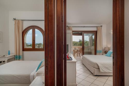 a hotel room with two beds and a balcony at Hotel Mariposas in Villasimius