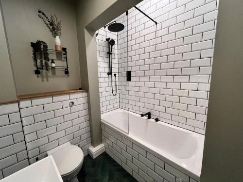 a white bathroom with a tub and a toilet at The Tops in Keswick