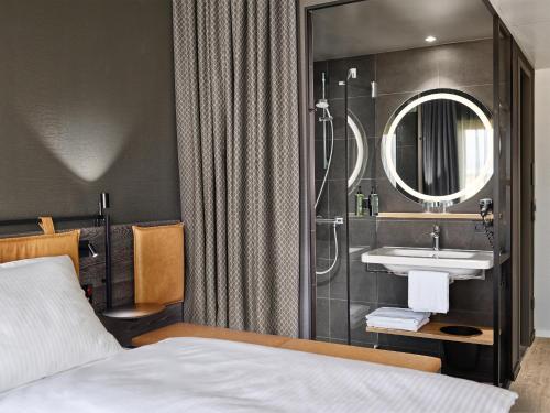 a bathroom with a bed and a sink and a mirror at H2 Hotel Saarbrücken in Saarbrücken