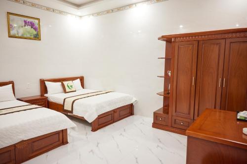 a bedroom with two beds and a wooden cabinet at Kiều Tiên Hotel in Long Thành