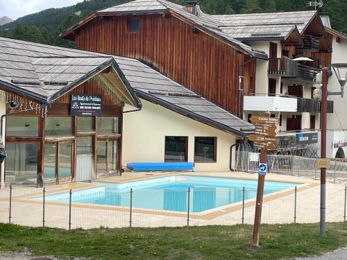 un immeuble avec une piscine devant un immeuble dans l'établissement Appartement 6 pers les Orres 1800 - Piscine chauffée Sauna, aux Orres