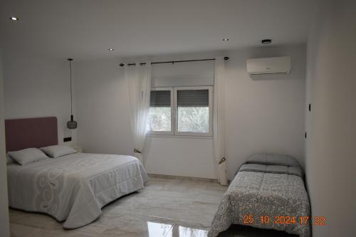 a white bedroom with two beds and a window at Entre Olivos in Níjar