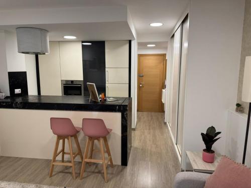 a kitchen with two bar stools and a counter at Estudio centrico de lujo in Vigo