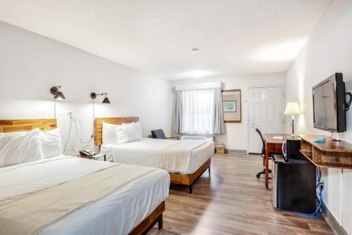 a hotel room with two beds and a flat screen tv at The Guest Lodge Gainesville in Gainesville