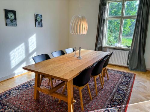 a dining room table with chairs and a large window at Seegut Hovmantorp in Hovmantorp