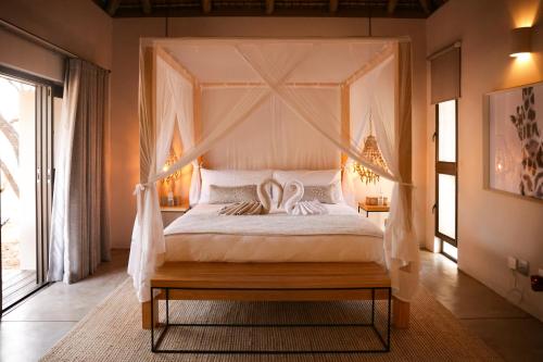 Un dormitorio con una cama con dosel con dos cisnes. en Villa Kudu - Exclusive and Serviced Safari Villa near Kruger Park, en Hoedspruit