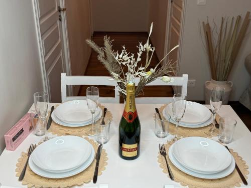 - une table avec des assiettes blanches et une bouteille de vin dans l'établissement Nest in Heart of Épernay, à Épernay