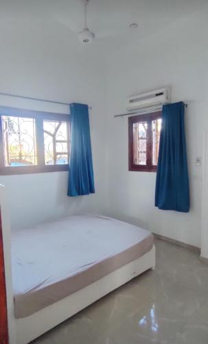 a bedroom with a white bed with blue curtains at Pro Luxor guest house in Luxor