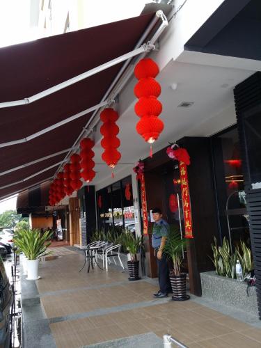 a man standing in front of a building with red lanterns at D Elegance Hotel Nusajaya in Nusajaya