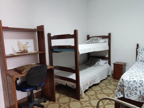 a room with two bunk beds and a desk and a chair at Colonial Praiano in Guarapari
