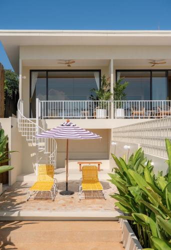 a house with two chairs and an umbrella on a patio at rocco villa in Ko Larn