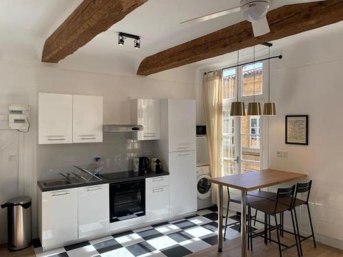 une cuisine avec des armoires blanches et une table avec des chaises dans l'établissement Le Prêcheur, à Aix-en-Provence