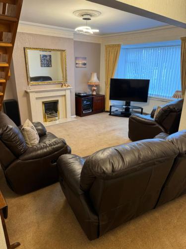 a living room with a leather couch and a television at Linden Ave Bungalow in Thornton
