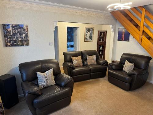 a living room with two leather chairs and a staircase at Linden Ave Bungalow in Thornton
