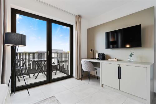 a room with a desk and a balcony with a television at Comfort & Style in Vibrant Luxembourg Coliving in Luxembourg