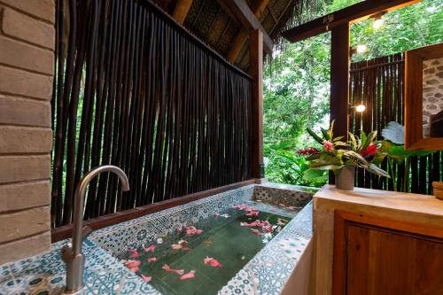 a bathtub in the middle of a porch with flowers in the water at Canto Tayrona Ecolodges in Buritaca
