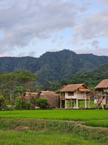 a group of houses with mountains in the background at PANAKLUEA Cottage & Crafts - พนาเกลือ in Ban Kham