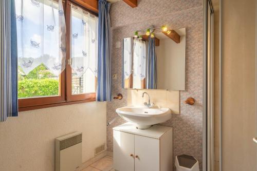 une salle de bain avec un lavabo, un miroir et une fenêtre dans l'établissement Chaleureuse maison les mouettes, aux Mathes