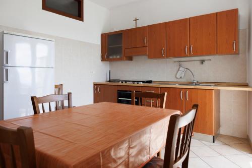 a kitchen with a wooden table with chairs and a kitchen counter at Casa Vacanza Iolanda in Mafalda