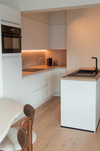 a kitchen with white cabinets and a table and chairs at Design appartement op toplocatie in Knokke in Knokke-Heist