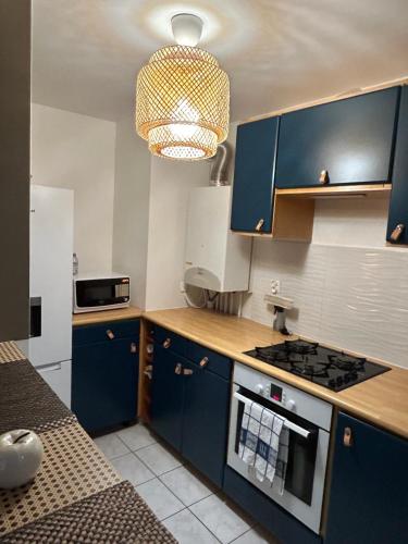une cuisine avec des placards bleus et un lustre dans l'établissement Appartement 1 chambre avec terrasse 5mn de Disney, à Magny-le-Hongre
