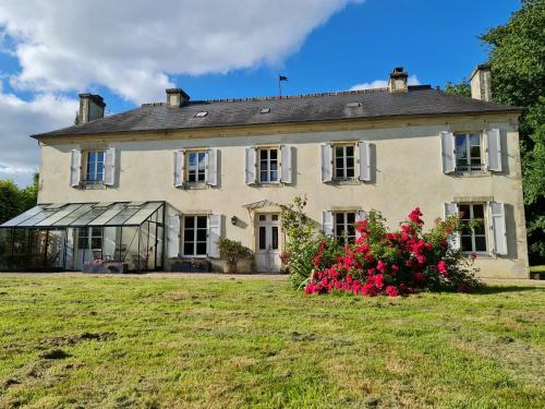 une vieille maison avec des fleurs dans la cour dans l'établissement Chambres d'hôtes de la Grande Maison, à Tour-en-Bessin