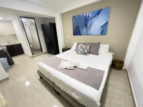 a bedroom with a large white bed with two shoes on it at Castellana 201-Apartaestudio en la Castellana con espacio trabajo in Armenia