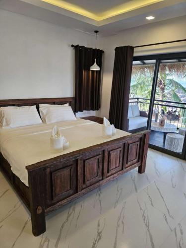 a bedroom with a large wooden bed and a balcony at Sunrise Beach Resort in Ko Chang