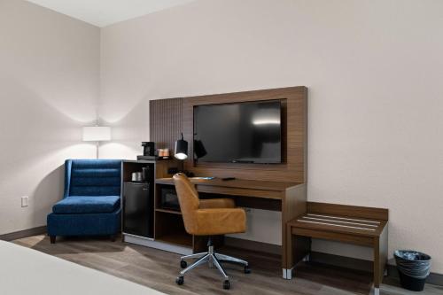 a hotel room with a desk and a tv and a chair at Clarion Pointe Lakeland I-4 in Lakeland