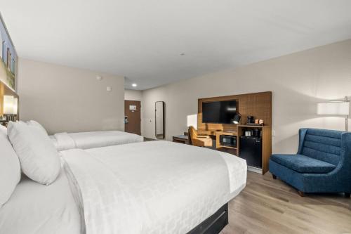 a hotel room with a bed and a blue chair at Clarion Pointe Lakeland I-4 in Lakeland