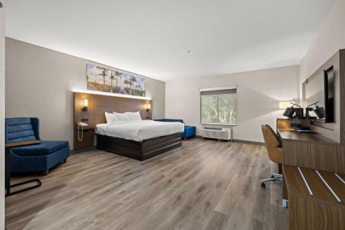 a hotel room with a bed and a blue chair at Clarion Pointe Lakeland I-4 in Lakeland