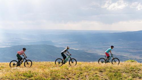 three people riding bikes on top of a hill at Western Lodge in Steamboat Springs