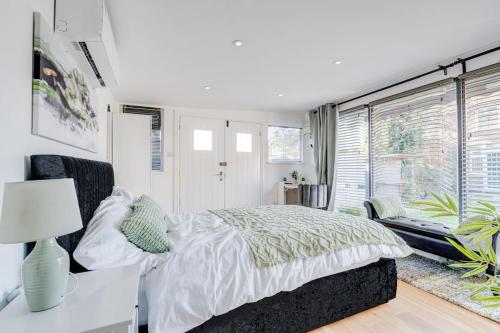 a white bedroom with a bed and a window at Waterbank Cabin in Lower Sydenham Station