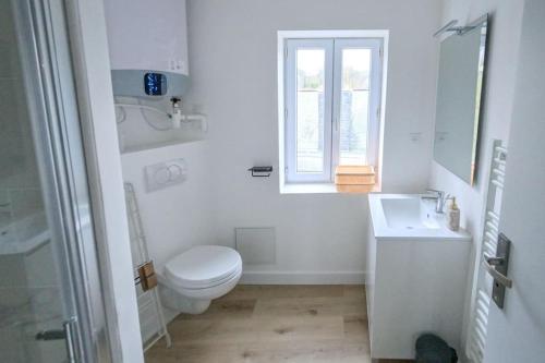 une salle de bain blanche avec des toilettes et un lavabo dans l'établissement Duplex Elégant - 250m plage, à Étretat