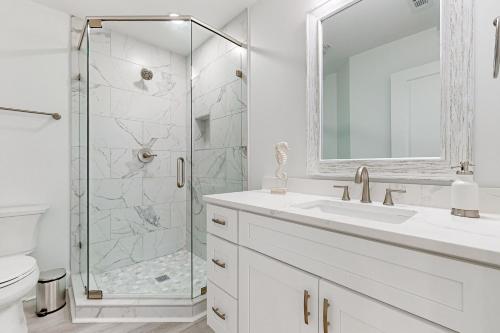 a white bathroom with a shower and a sink at Bahia Beauty - 3rd Floor in Navarre