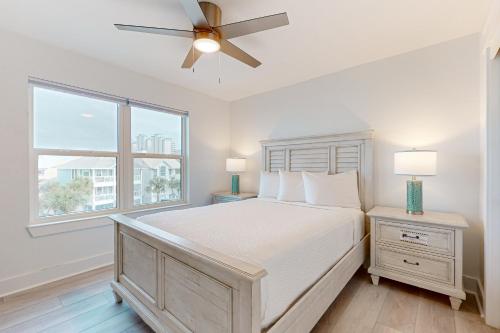a white bedroom with a bed and a ceiling fan at Bahia Beauty - 3rd Floor in Navarre