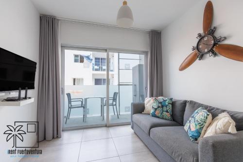 a living room with a couch and a sliding glass door at Hola Jag Corralejo Center iRent Fuerteventura in Corralejo