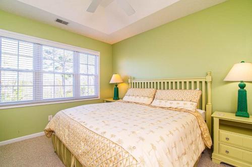 a bedroom with a bed with green walls and a window at Lakefront and 1 Block to Beach! Walk to Main St in Myrtle Beach