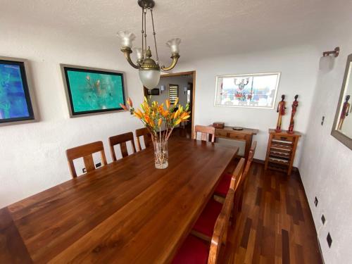a dining room with a wooden table and a vase of flowers at La mejor vista de Viña del Mar in Viña del Mar