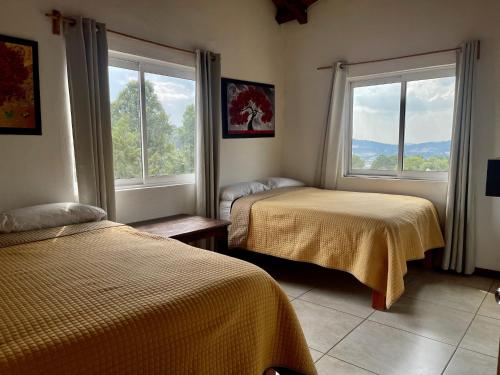 a bedroom with two beds and two windows at Herradura VIP Inn in Mazamitla