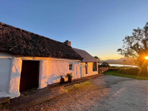 an old house with a thatched roof on a road at Private Thatched Cottage - with views in Letterkenny