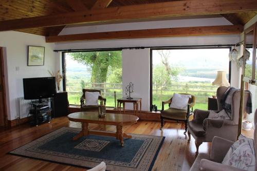 a living room with a table and a large window at Private Thatched Cottage - with views in Letterkenny