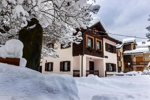 a house with snow on the ground in front of it at Champoluc Apartment in Champoluc