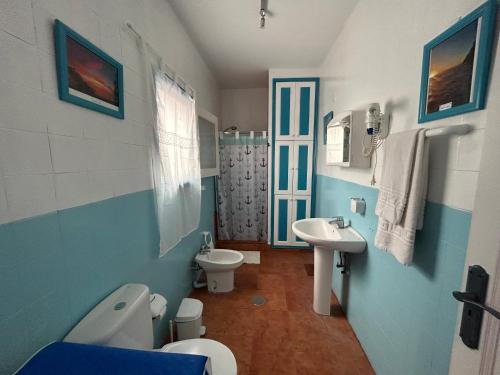 Un baño azul y blanco con inodoro y lavabo. en Apartamentos Buen Leon, en Playa de Tasarte