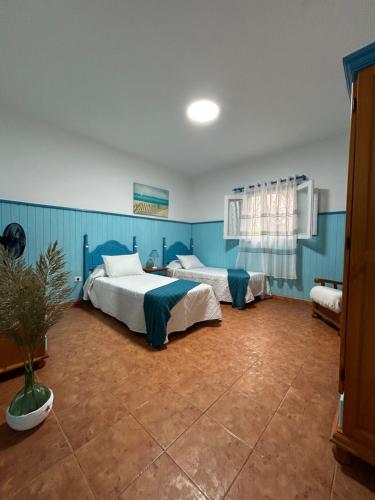 Dos camas en una habitación con paredes azules. en Apartamentos Buen Leon, en Playa de Tasarte