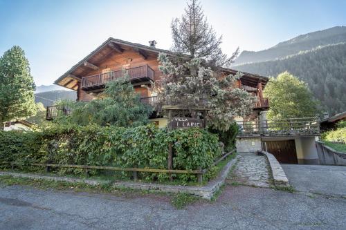 a wooden house with a fence in front of it at Champoluc Apartment in Champoluc