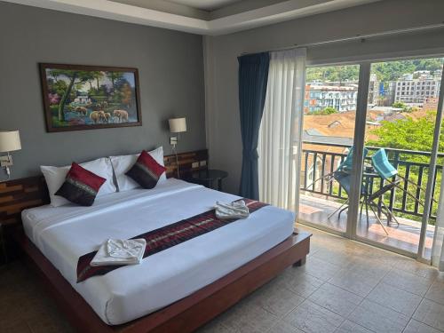 Un dormitorio con una cama grande y un balcón. en SawasdeeCiao Patong Guesthouse, en Patong Beach